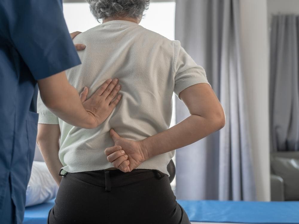 Chiropractor adjusting the back of an older man.