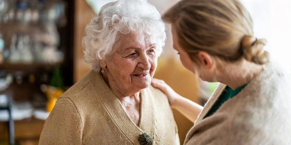 Young woman visiting an older woman with dementia at home.