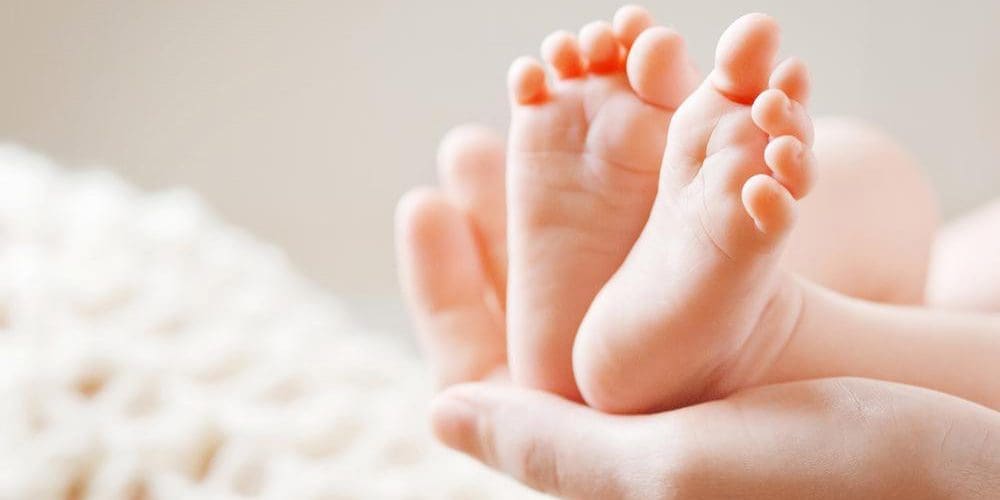 Mother holds a newborn baby's feet.