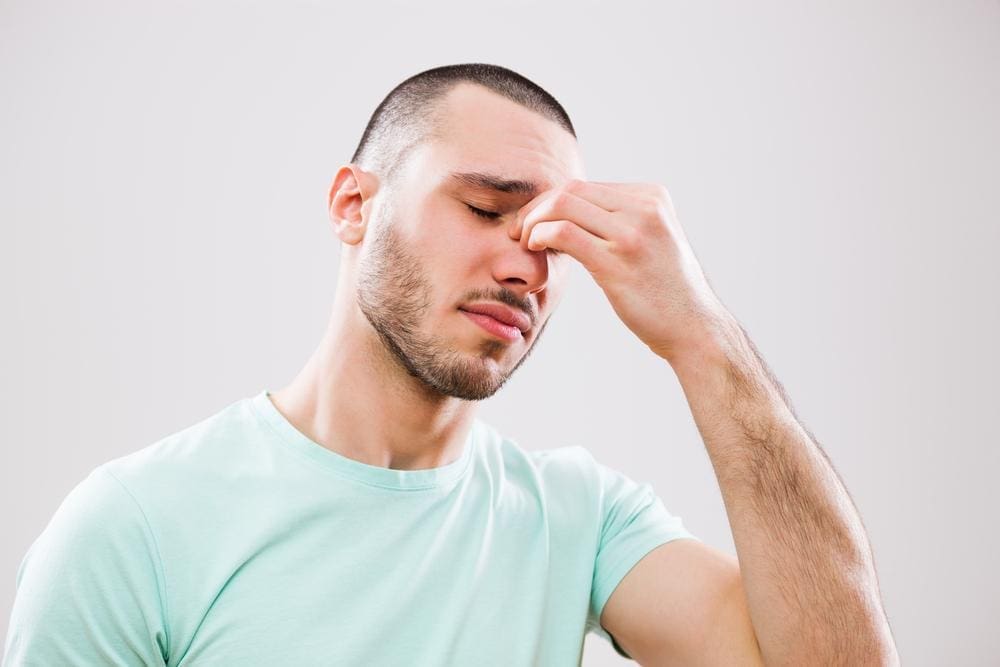 Young man experiencing sinus pressure and pain.
