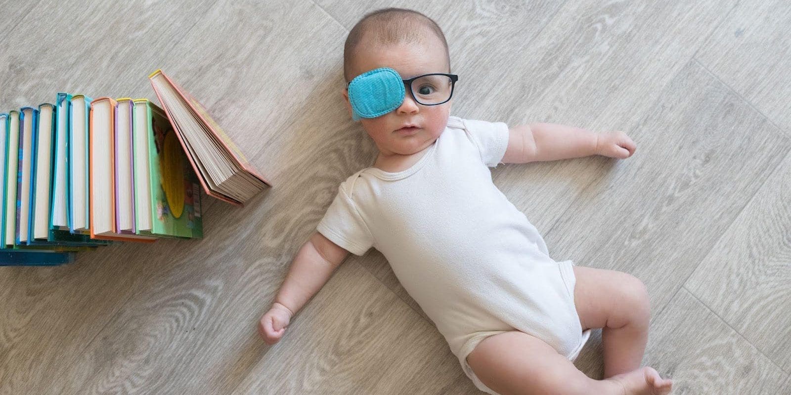 Infant wearing glasses with one lens covered with an eye patch.