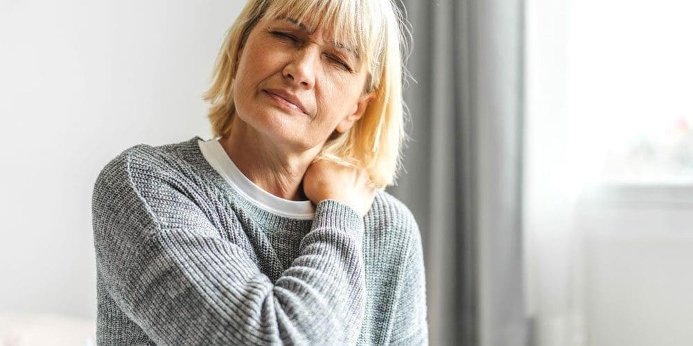 Woman rubbing her shoulder because of a brachial plexus injury.