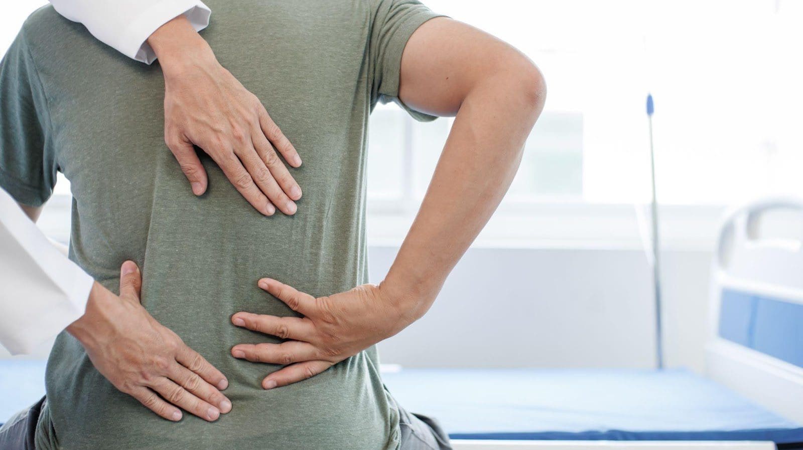 Chiropractor adjusts young man's back.