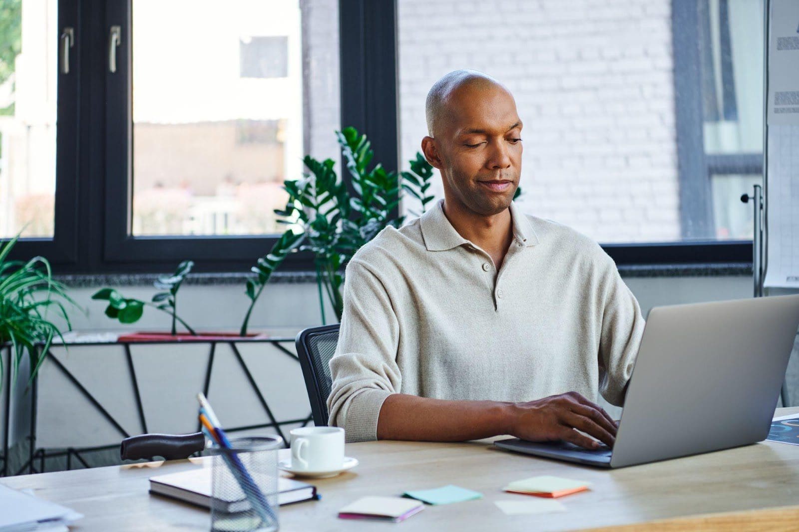 A middle-aged man sits at a table working on his laptop.