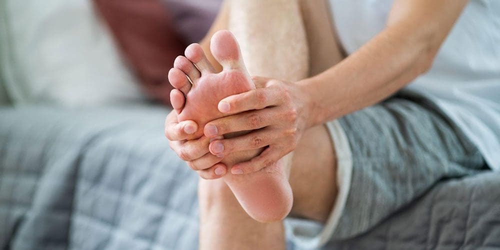 Man holding his foot because of pain in the ball of his foot.