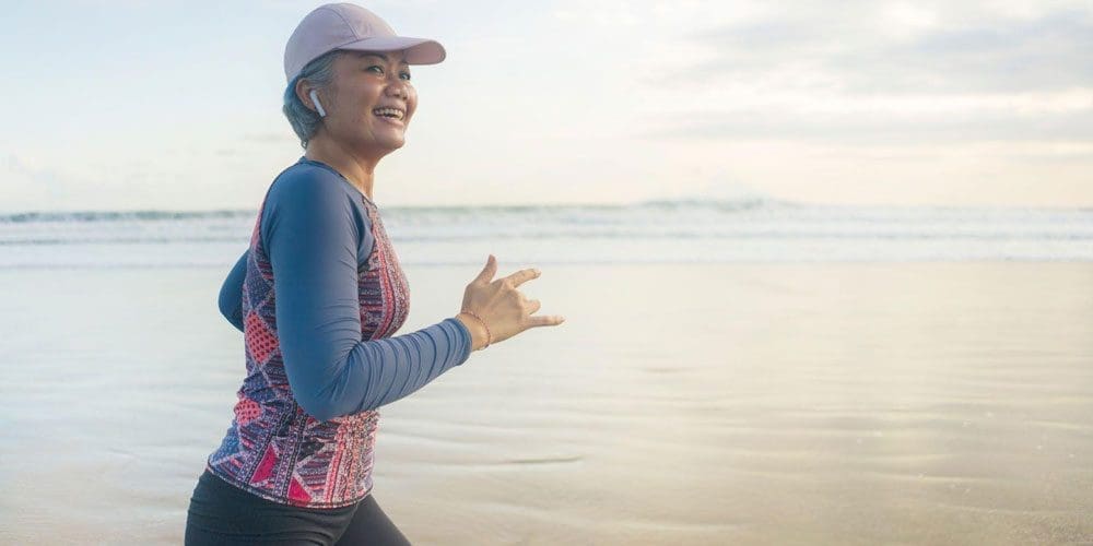 Middle-aged woman running on a beach.