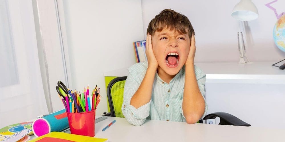 A boy with SPD covering his ears and yelling in a classroom.