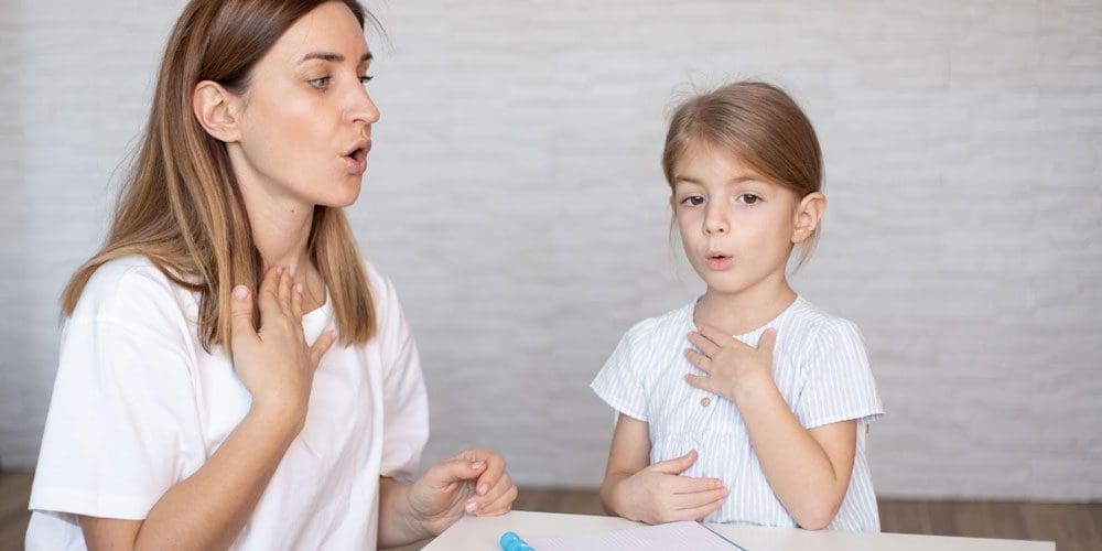 Young woman and little girl doing exercises for breathing and speaking.