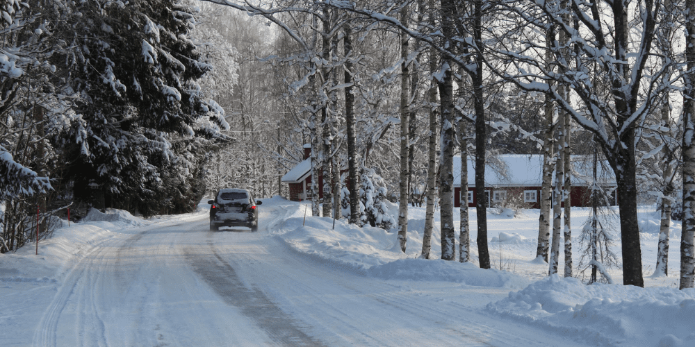 A car driving down an icy road in the country.