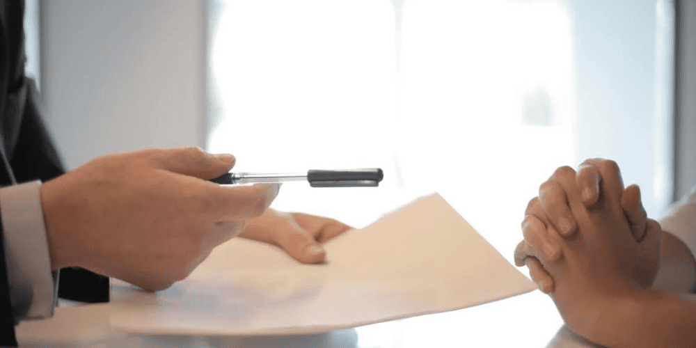 An insurance agent giving papers to sign to a women.