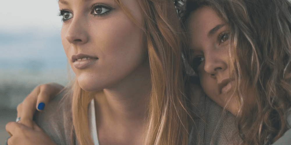 Two women hugging looking at the sunset