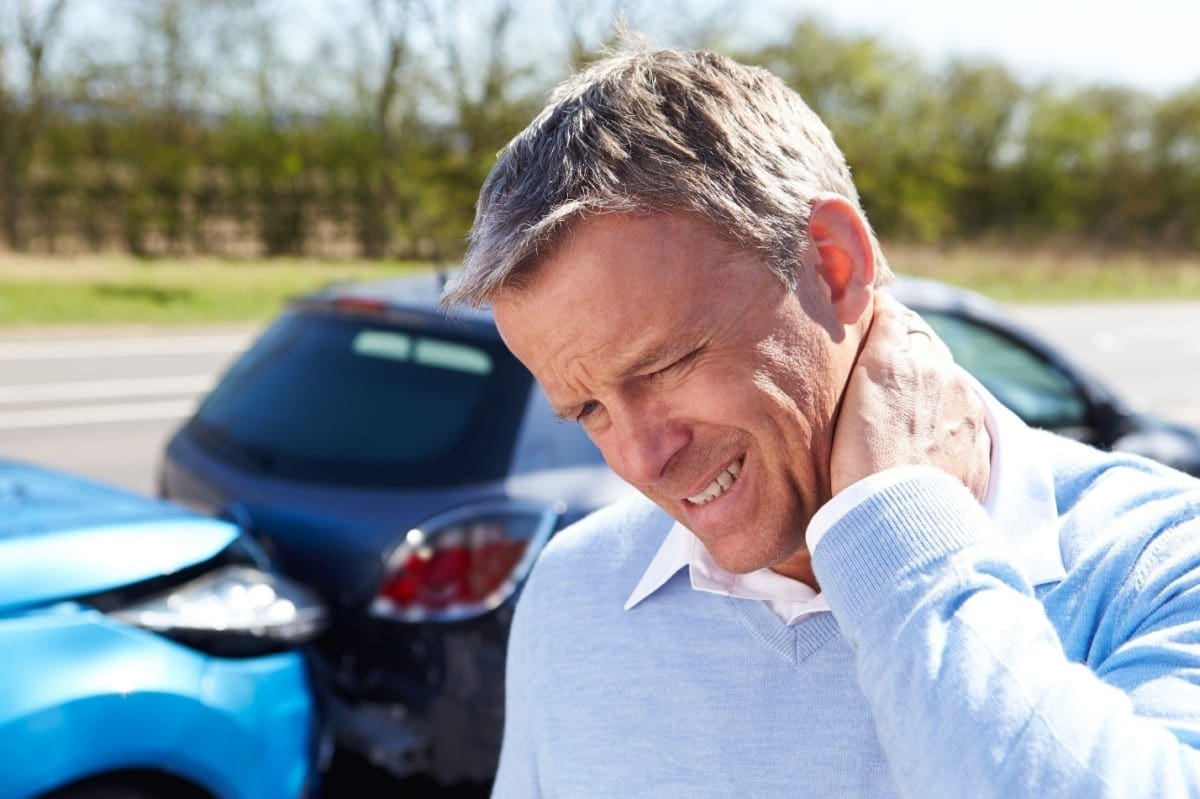 A man winces in pain from a neck injury after a car accident.