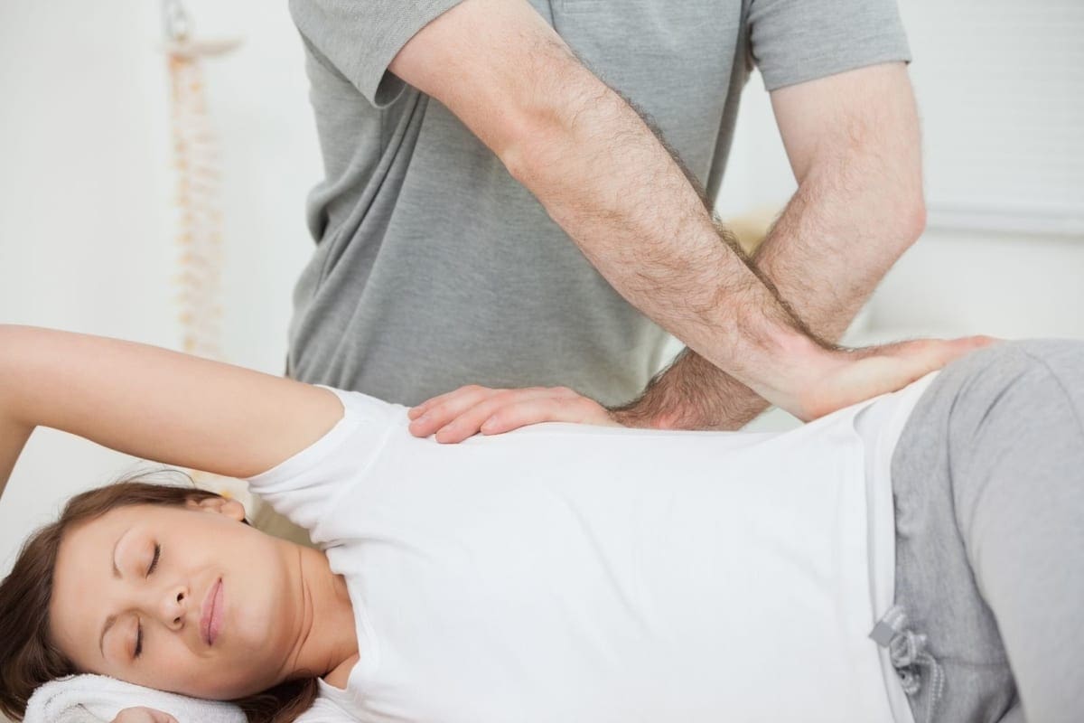 A chiropractor performing spinal adjustment on a woman.