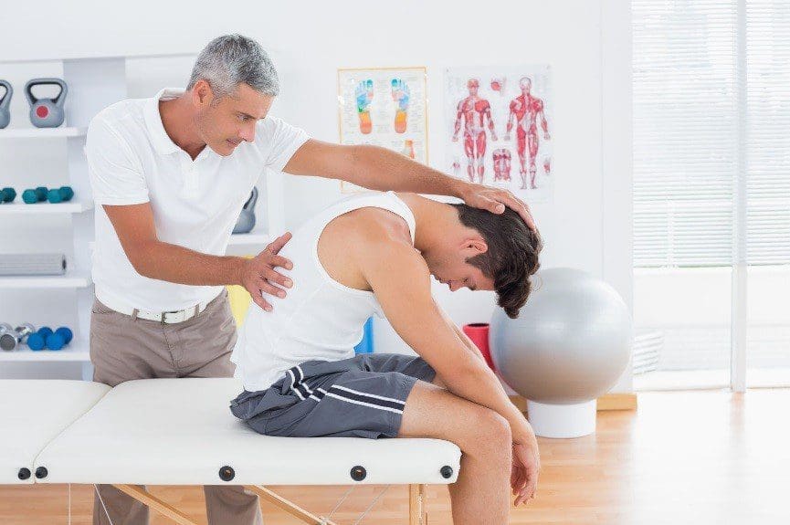 A chiropractor is administering treatment for back pain on a young man.