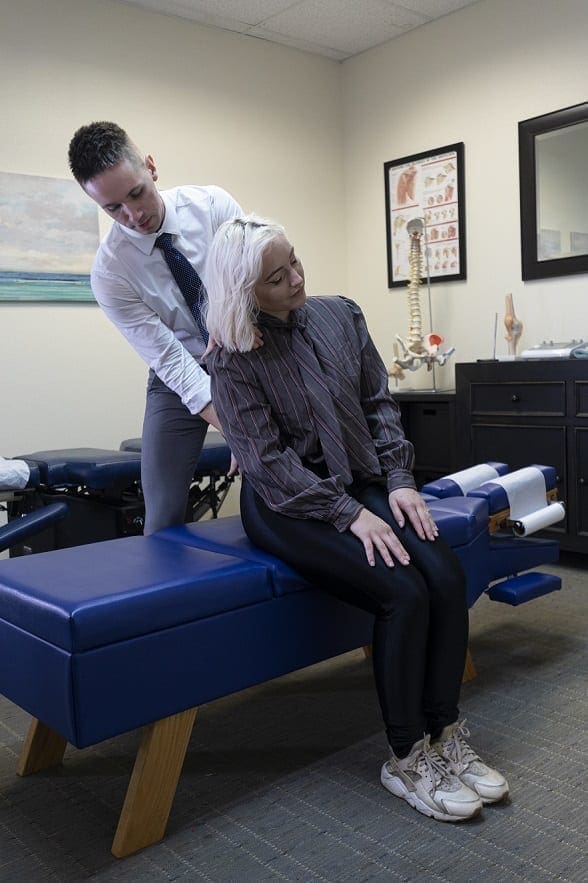 A woman is getting a spinal exam from a chiropractor in Portland.