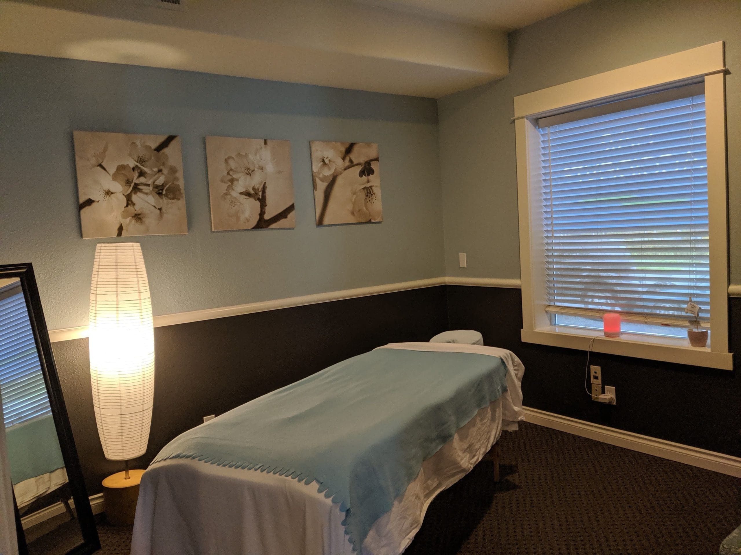 McMinnville Chiropractor massage therapy room with massage table, window and floral wall art.