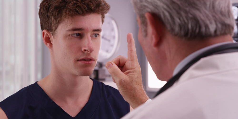 A doctor is doing tests to diagnose a man for a concussion.