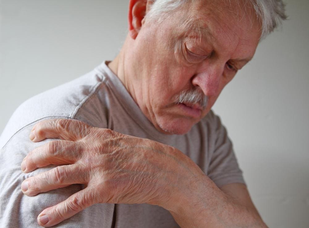 A man his holding his shoulder because he is suffering from bursitis. 
