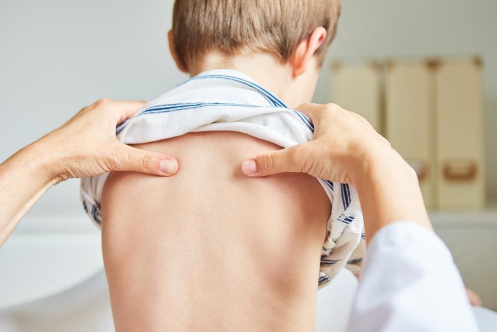 A young boy's back is being examined by a chiropractor. 
