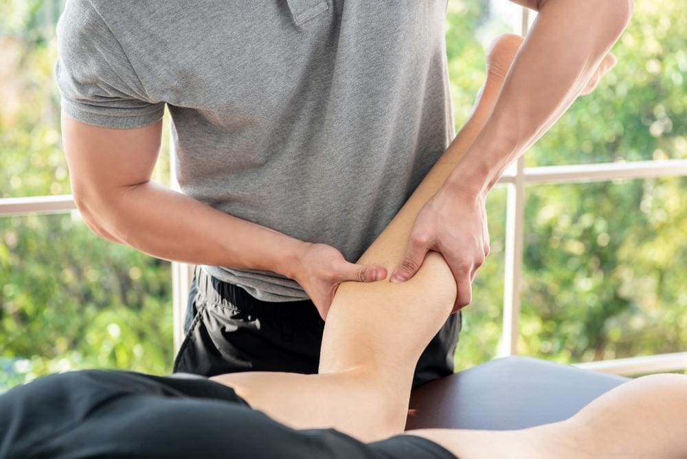 A chiropractor is treating a patient's torn muscle in the leg.