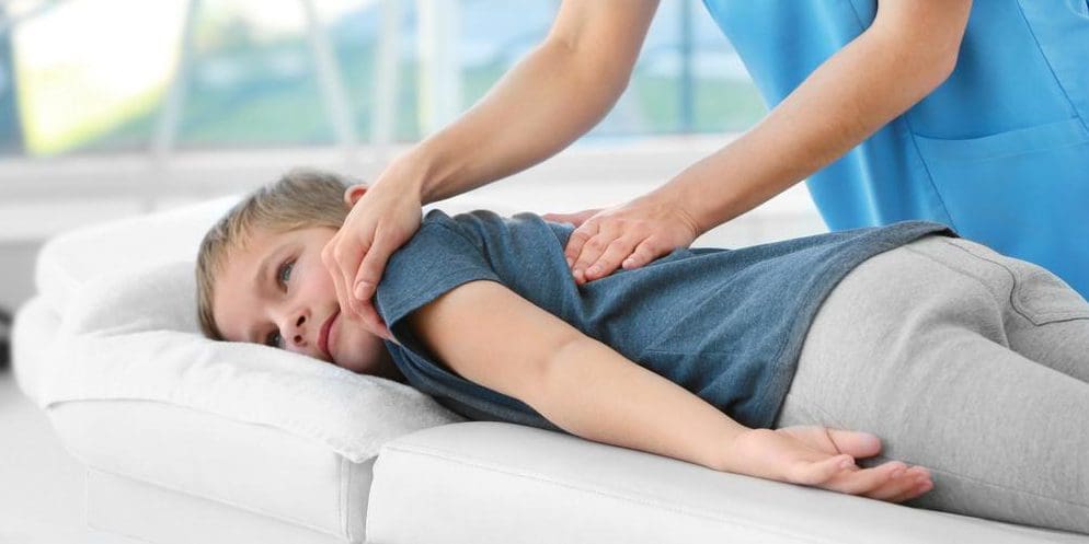 A child is getting a gentle chiropractic spinal adjustment.
