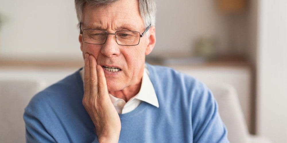 An older man is suffering pain in his face from the trigeminal nerve.
