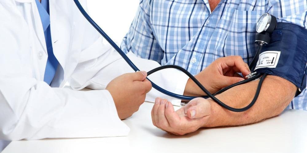 A man is getting his blood pressure checked by a doctor.