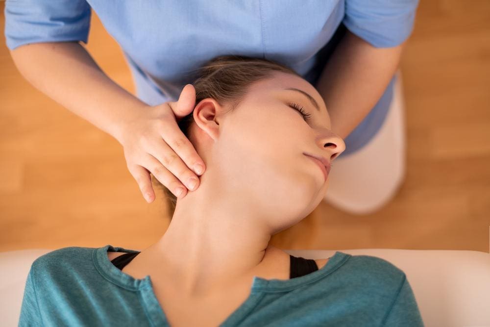 Chiropractor massaging young woman's neck.