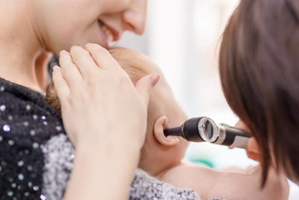 Doctor examining child's ear with an otoscope.