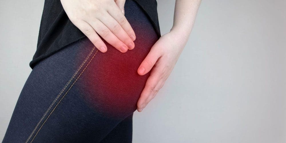 Woman holding her hip and backside from piriformis syndrome pain.