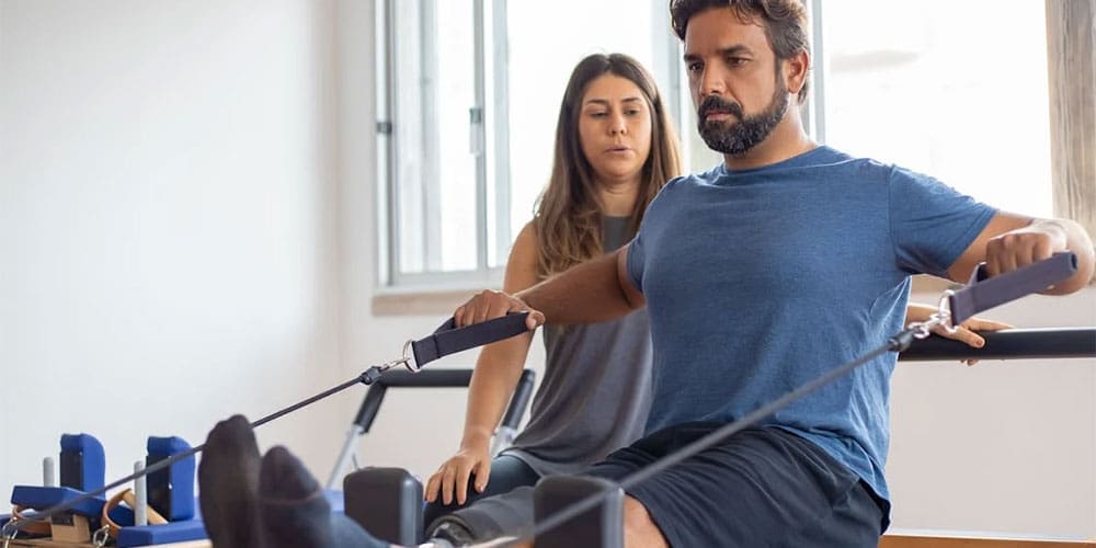 Man exercising in physical therapy with female chiropractor