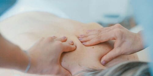 Chiropractor hands on the upper back of female patient